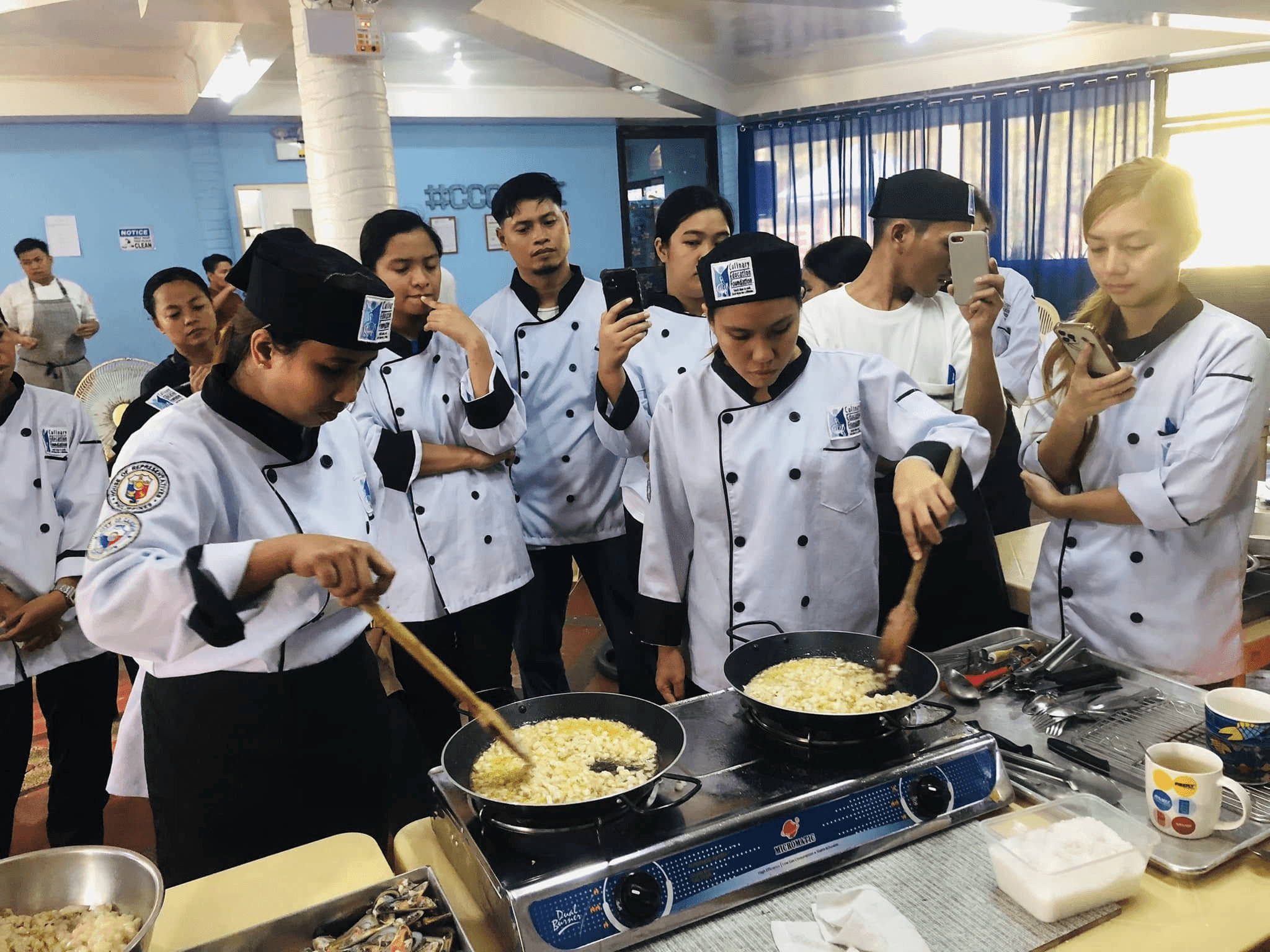 Culinary students in white coats working together in a training kitchen