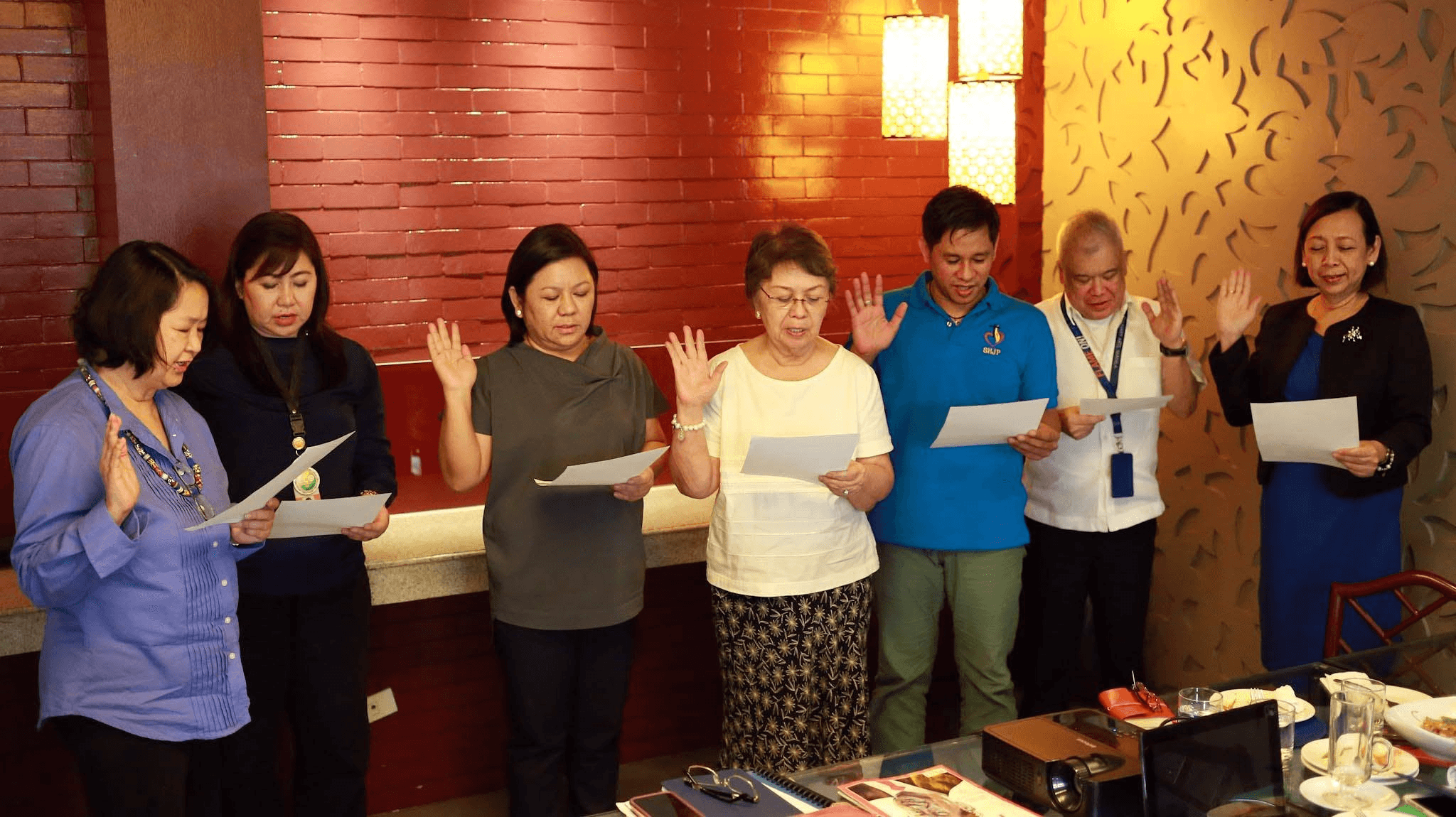 Susana Guerrero and colleagues with hands raised during a gathering