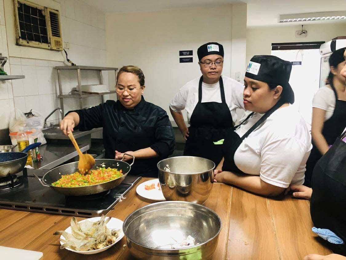 Volunteer instructor Chinie cooking with scholars in the kitchen